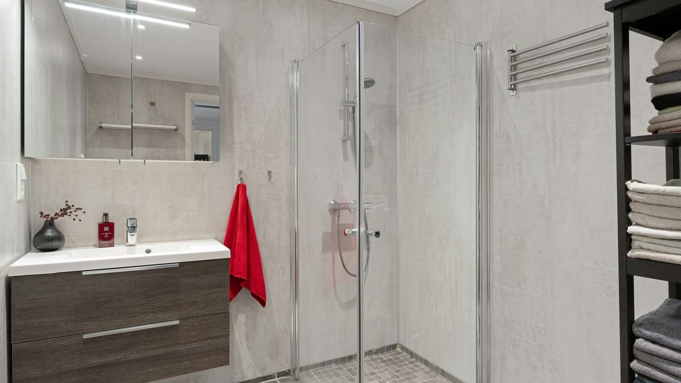 A bathroom with a stand up shower next to a sink